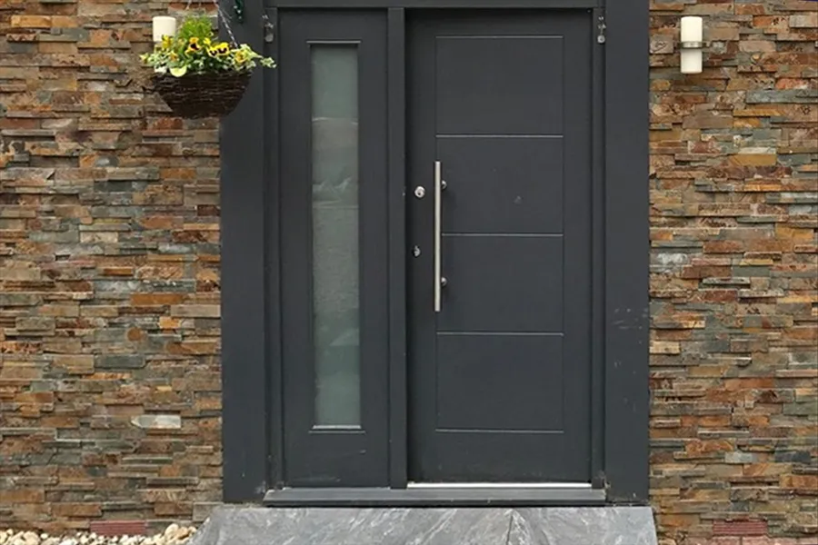 Modern black front door with split face brick tiles across front exterior of house,