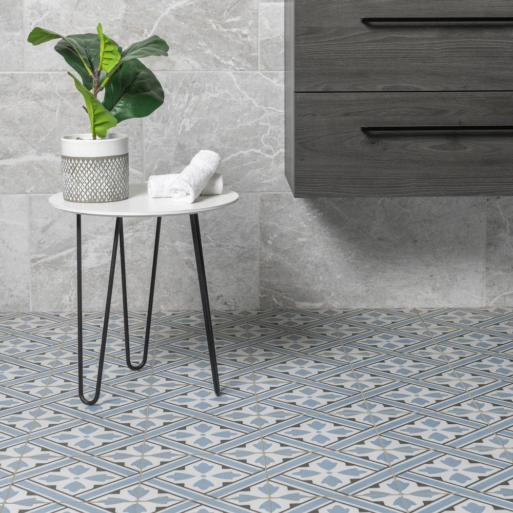 Patterned blue bathroom floor tiles with grey wall mounted vanity basin and stone effect grey wall tiles. 