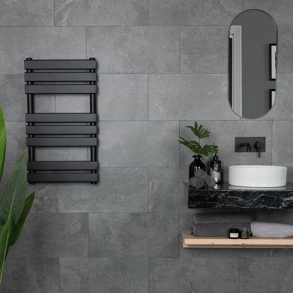 Dark grey and black bathroom with wall mounted heated towel rail and wall mounted sink. 