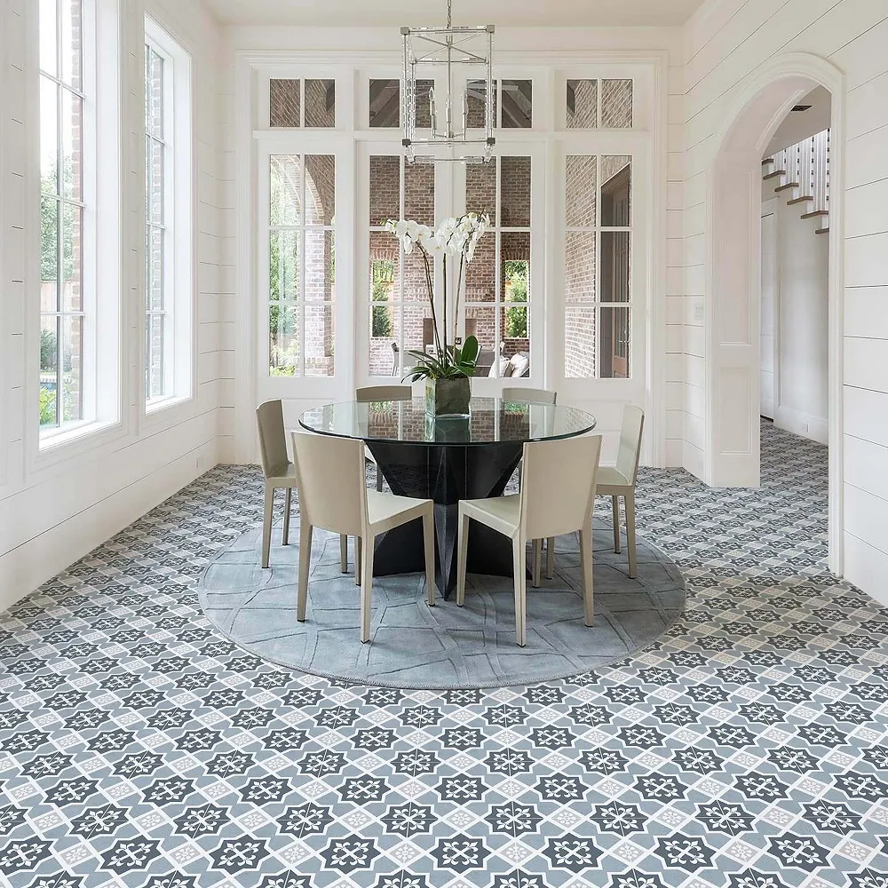 Round dining table in centre of grand room with blue and white patterned tiles across the floor. 